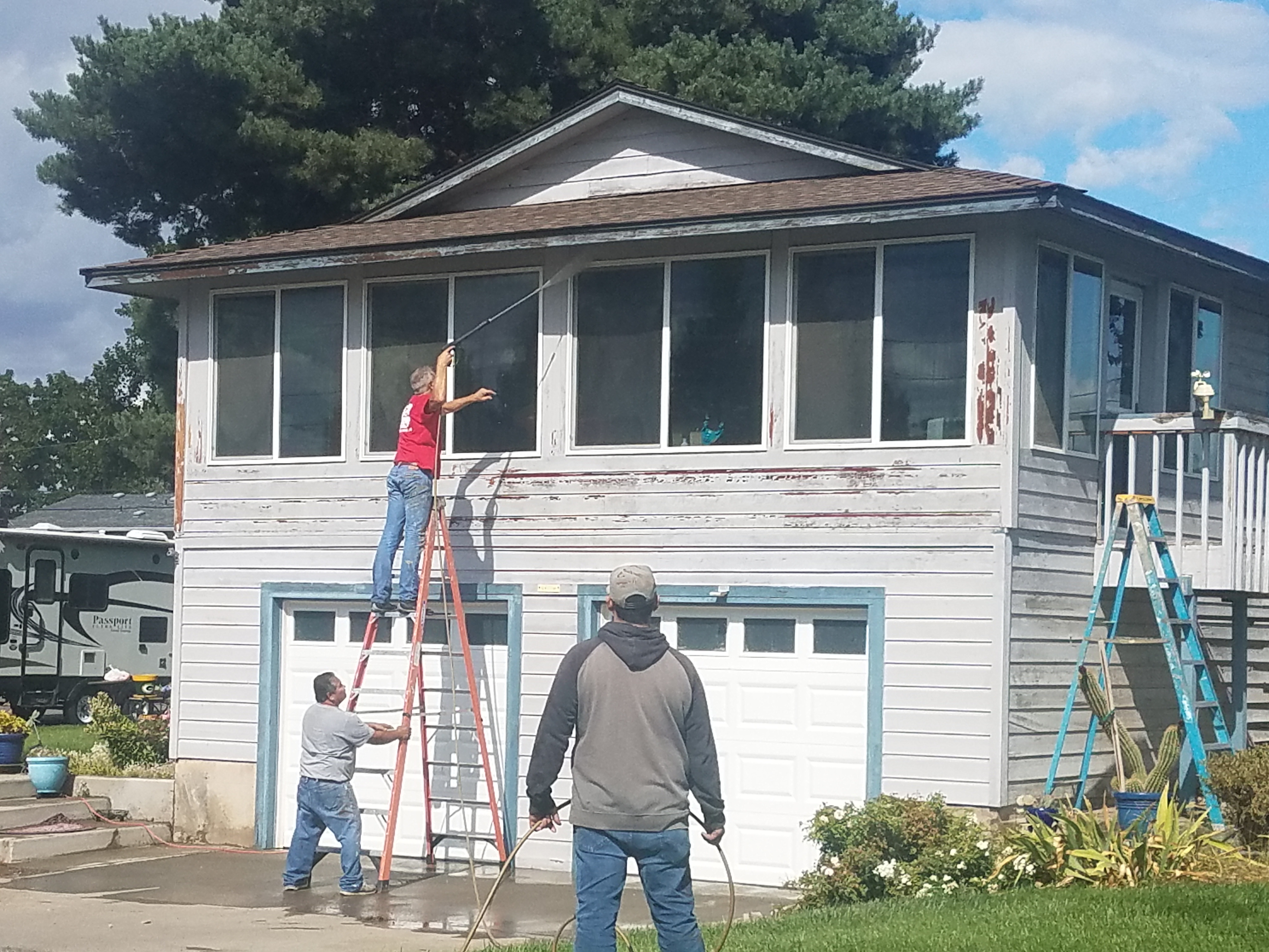 Crew members scraping and prepping a home exterior for painting
